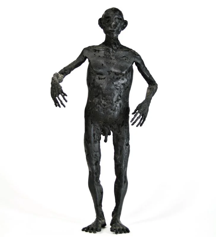 A standing steel figure with a broad torso and hands held beside its body.