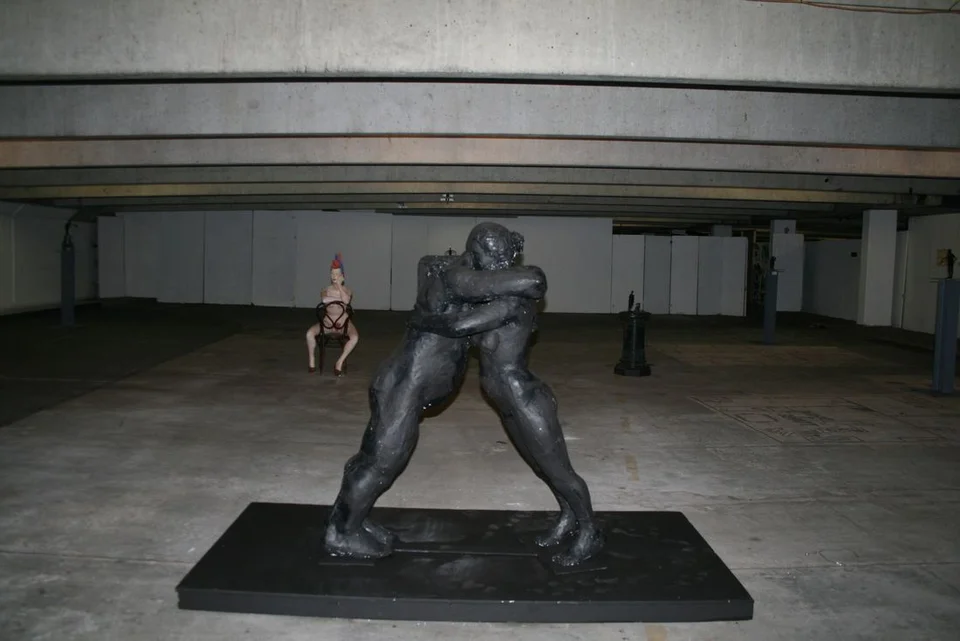 Two large intertwined figures on a low platform in a spacious interior.