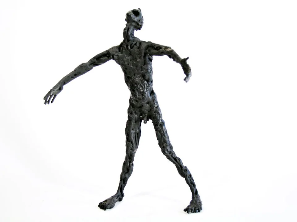 A dark steel figure with its head tilted back, open mouth and arms spread.