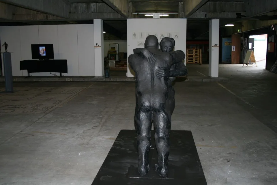 Two large intertwined figures on a low platform in a spacious interior.