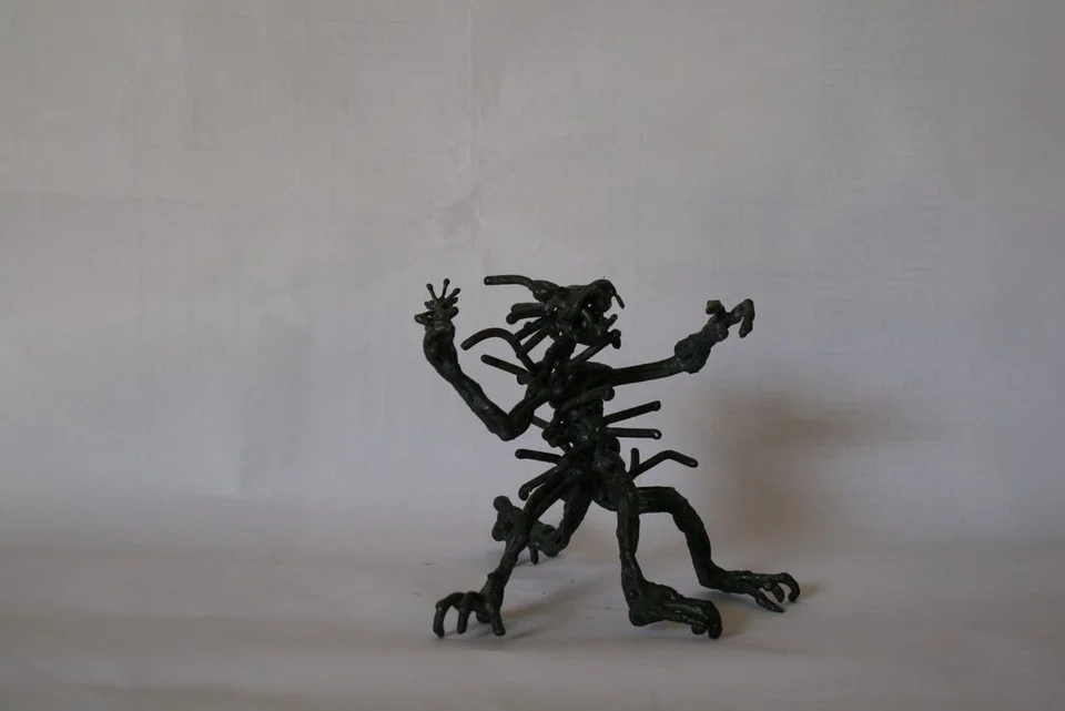 A small steel creature with many projecting limbs and a long tail.