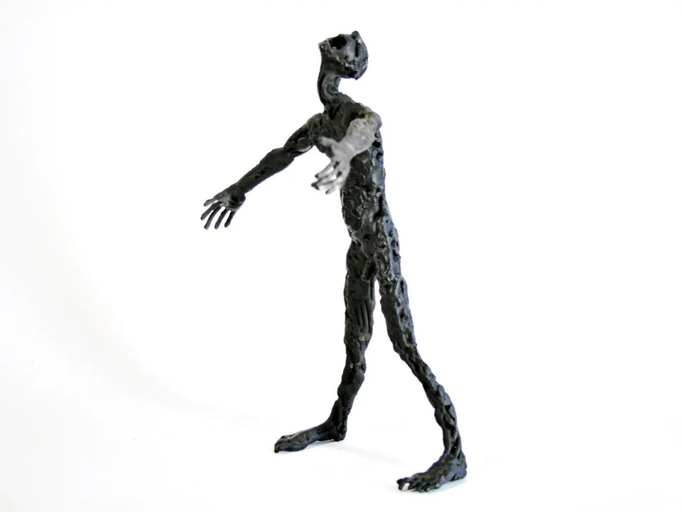 A dark steel figure with its head tilted back, open mouth and arms spread.