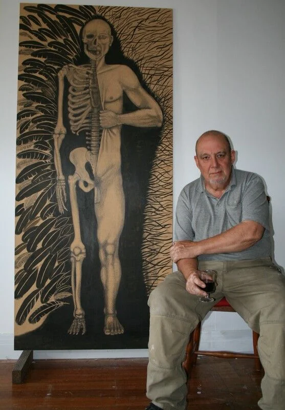 Gordon seated beside a large anatomical drawing, holding a glass.