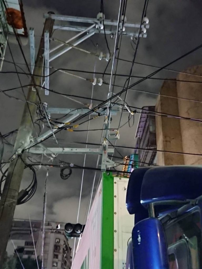 一輛長榮貨櫃車因車身過高，再經過巷口時，不慎勾到電線。（圖／讀者提供）