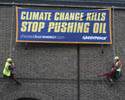 Greenpeace volunteers dangle with a banner reading "climate change kills - stop pushing oil"