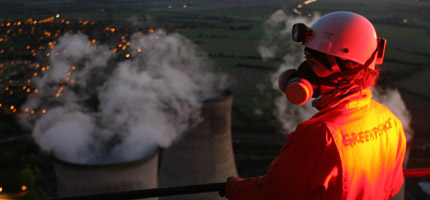 A Greenpeace volunteer looks down at the chimneys at Didcot power station