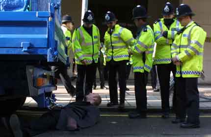 An activist chained to a truck outside the Oil and Money conference