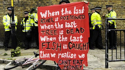 A climate camp protester holds up a banner in front of police