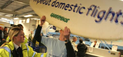 A Greenpeace activist is moved on by a policewoman at Newquay airport