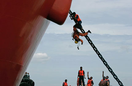 A policeman pushes a Greenpeace climber down from the anchor chain of the Gran Couva 