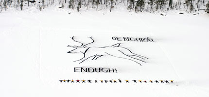 10 young Sàmi people and Greenpeace volunteers use charcoal on a frozen river to say 'enough' to the Finnish Government