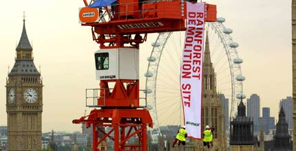 Greenpeace volunteers hang a banner from a crane opposite the Houses of Parliament in 2003