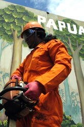 Protesters sawing through a huge wooden wall depicting Indonesia's rainforests