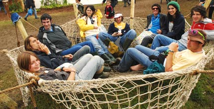 Visitors to the Greenpeace field at Glastonbury festival sitting in a hammock