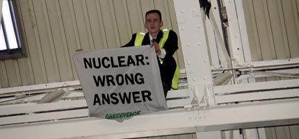 A climber at the CBI conference holds a banner reading NUCLEAR: WRONG ANSWER