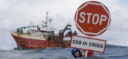 A Greenpeace activist swims in front of a Scottish fishing trawler