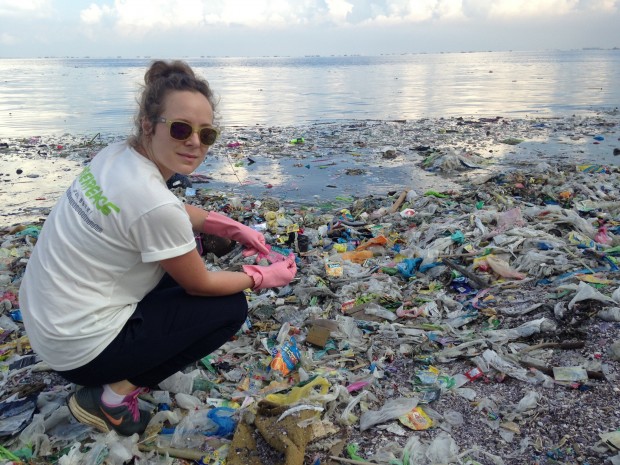 Greenpeace campaigner collecting drinks straws from a beach in Manila