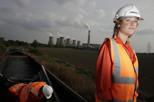 Greenpeace activist on top of a coal train with power station in the background