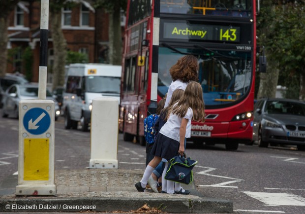 Children crossing a road near a red London bus