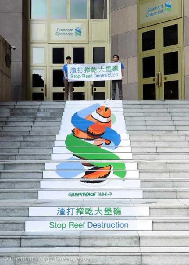 Hong Kong Greenpeace activists unfurl a huge stair-riser banner outside the HQ