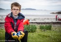 Child on a beach holding old bottle caps