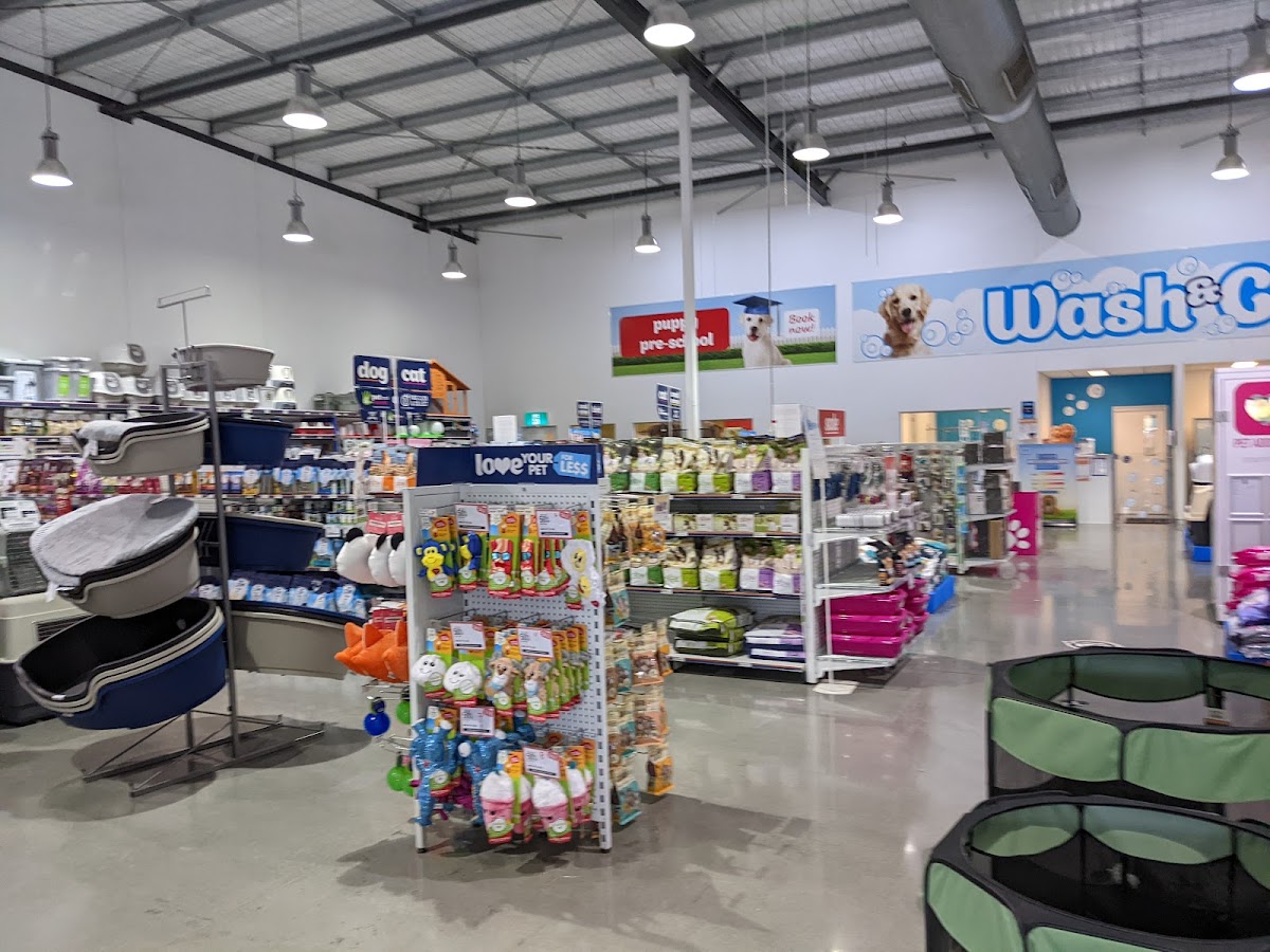 Interior of a pet store with shelves stocked with dog and cat supplies, including toys and grooming products.