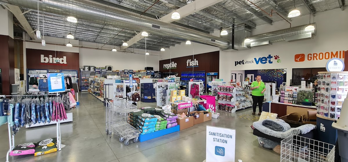 Interior of a pet store with shelves stocked with products and a sanitization station visible.