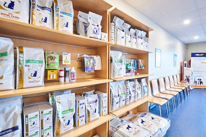 Interior of a veterinary clinic or grooming salon with shelves stocked with pet food and cat supplies.