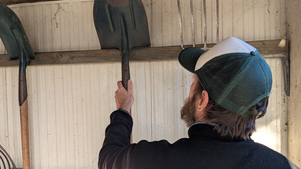 Man organising garden tools in a shed