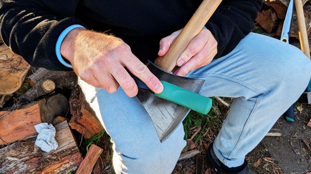 Person sharpening axe with whetstone