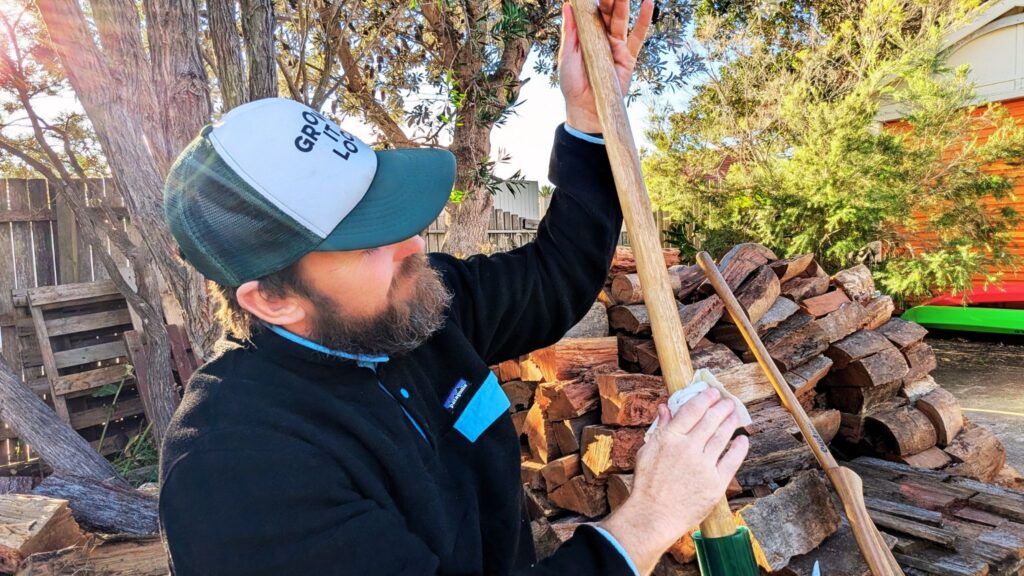 Man maintains wooden tool outdoors
