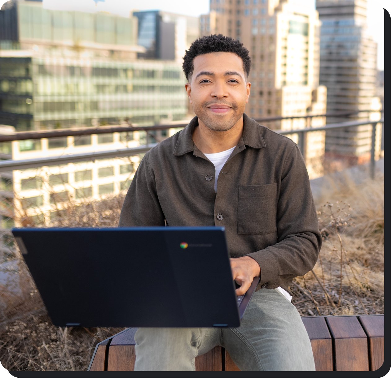 Man seating on rooftop with a laptop.