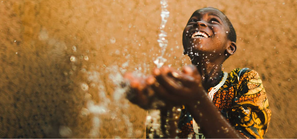 Un bambino sorride mentre gioca con l’acqua