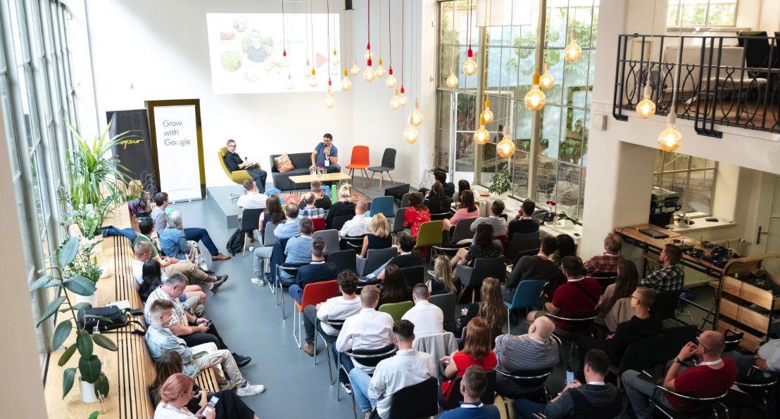 Participants of Grow with Google Business Academy sit in a conference room listening intently to speakers at the front of the room.