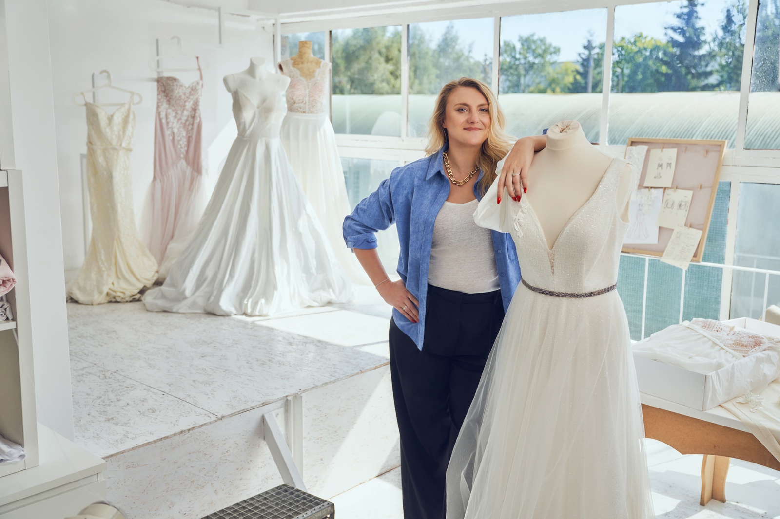 Uczestniczka programu Firmy Jutra, właścicielka Lara Levai w swoim salonie sukien slubnych, stoi uśmiechnięta, oparta o jedną z sukni.