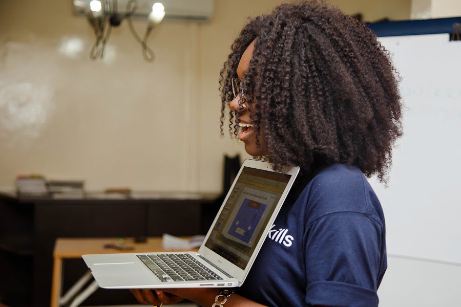 Teacher holding a computer shows her students some website.