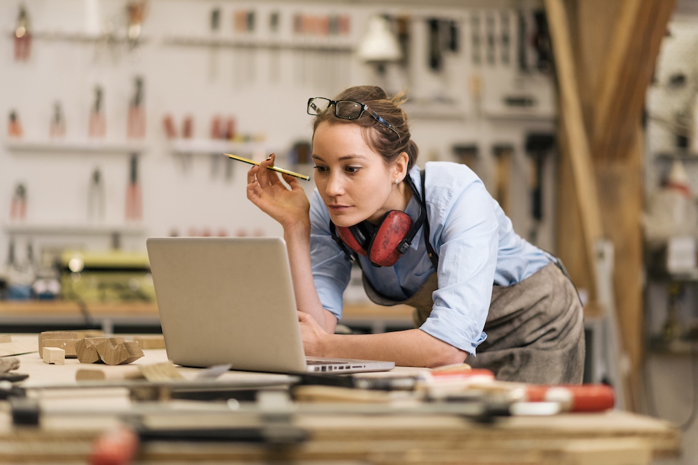 Egy nő dolgozik a laptopján egy workshopon, ceruzával a kezében.
