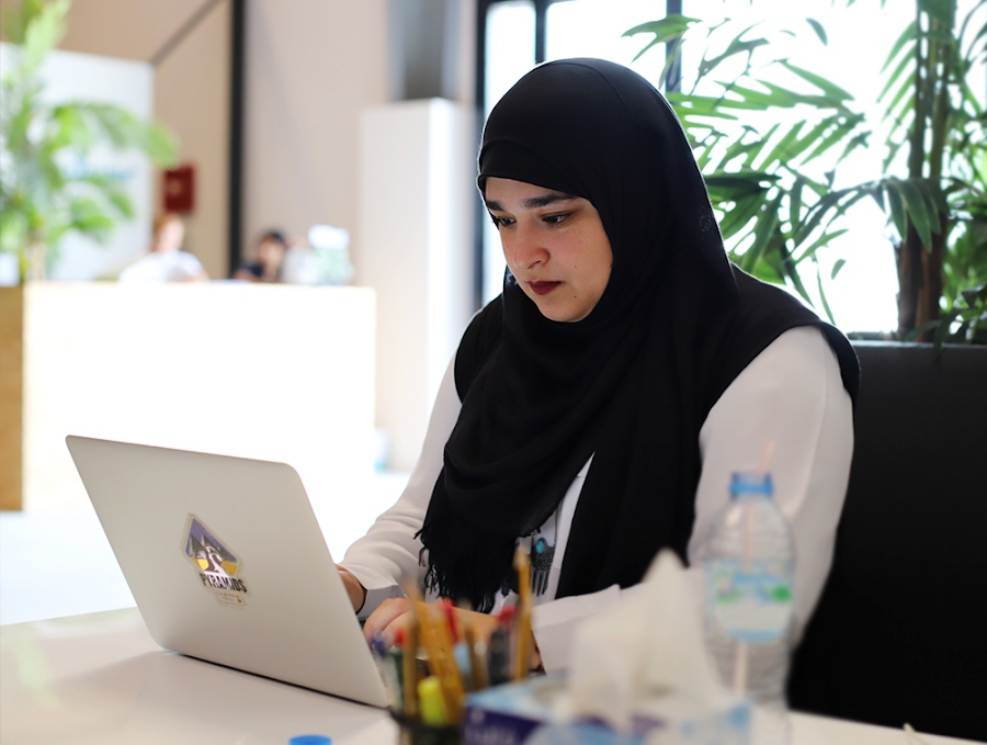 A woman works at a laptop in an office space.