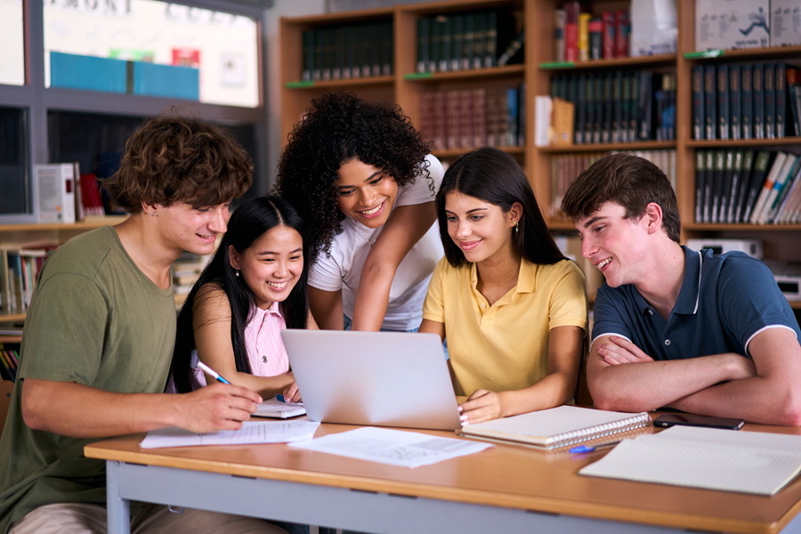 A laptop resting on a stack of books, representing school devices ready for buyback