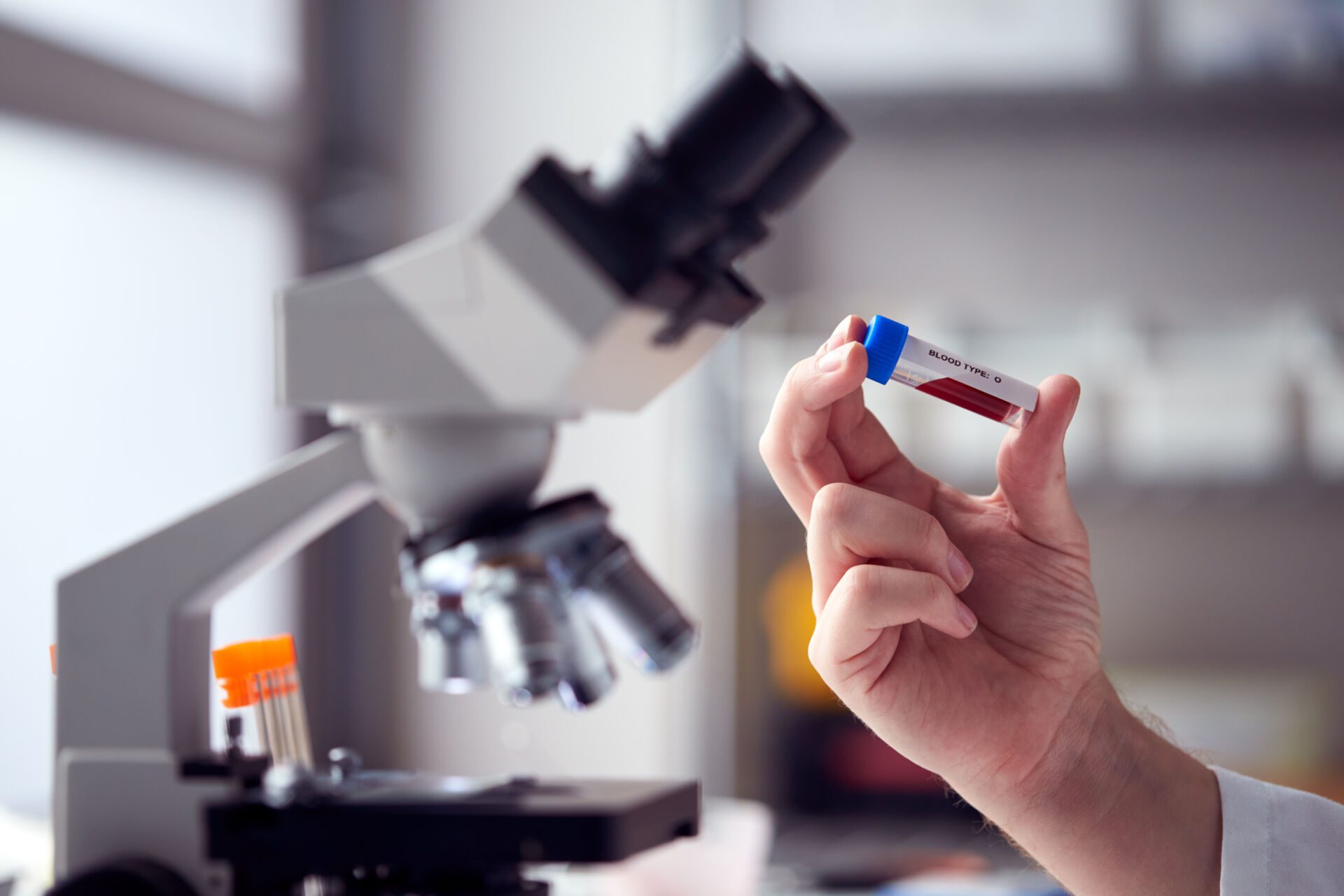 Close Up Of Male Lab Worker Or Phlebotomist Analysing Blood Samples In Laboratory With Microscope Insurance for Phlebotomists