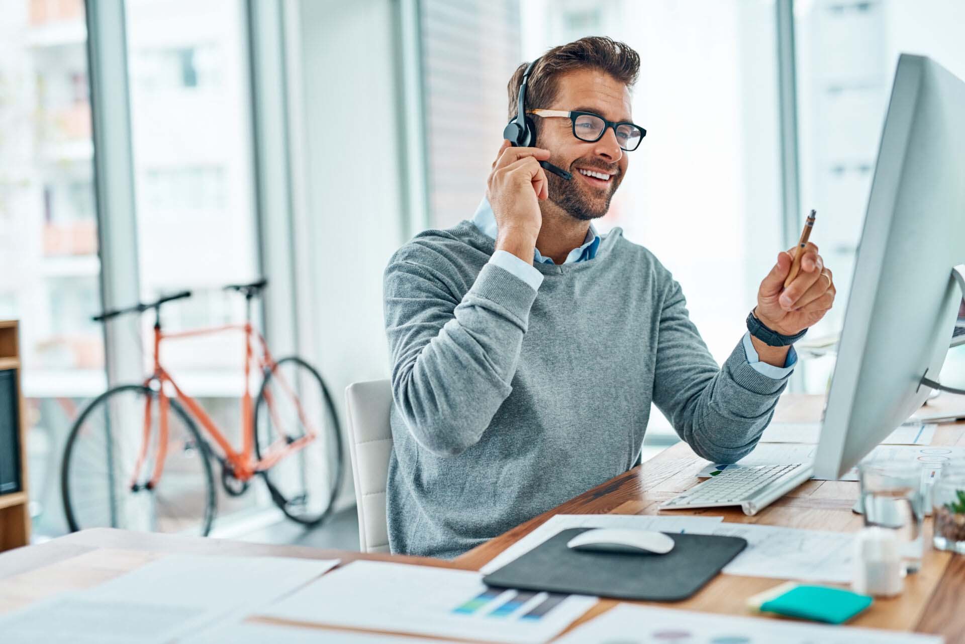 Call center, man and consultant consulting with a smile doing internet telemarketing sales in an agency office. Young, computer and happy male employee working on customer service for support Insurance for Talent Agencies