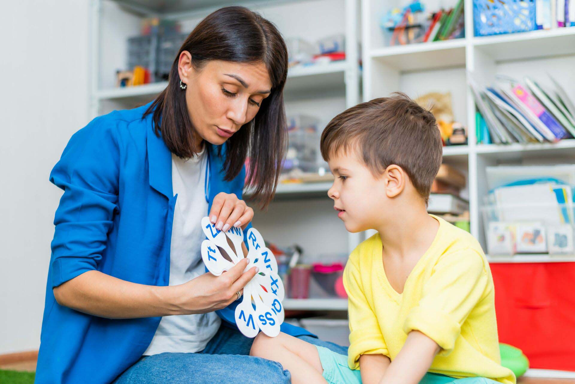 A cute boy with a speech therapist is taught to pronounce the letters, words and sounds. Insurance for Speech Therapists