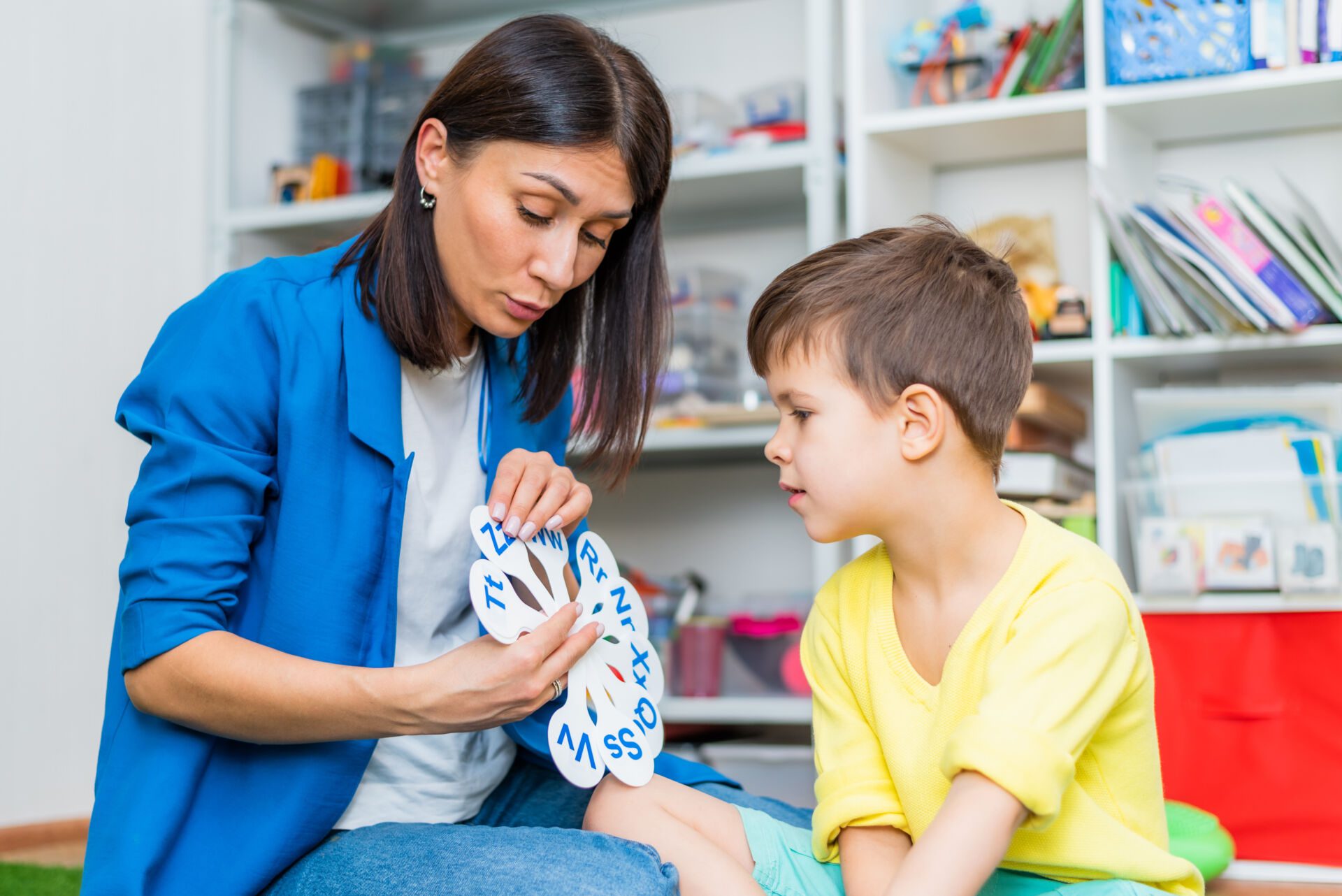 A cute boy with a speech therapist is taught to pronounce the letters, words and sounds. Insurance for Speech Therapists