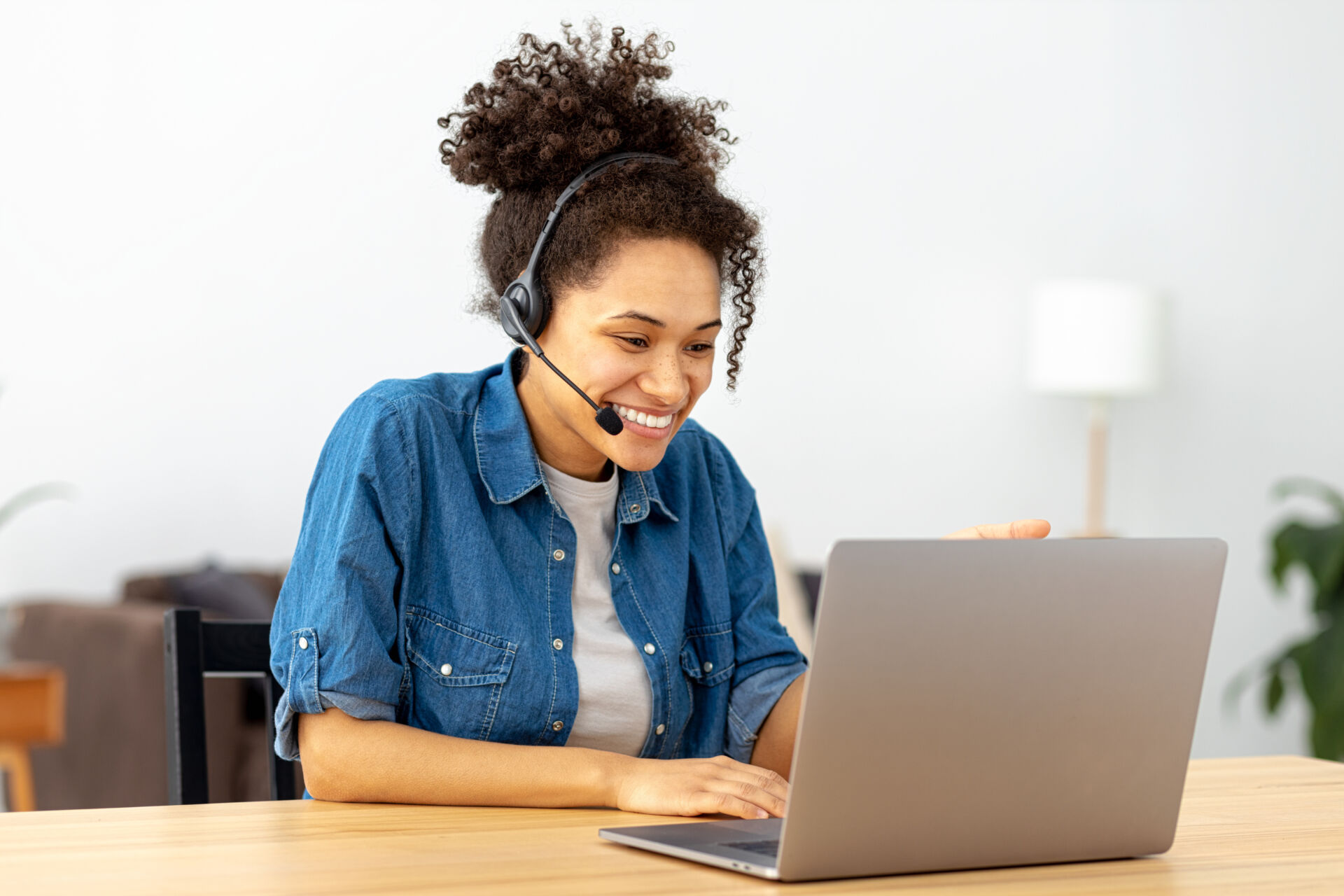 Successful African American woman in headset, office employee or call center worker sitting in a modern office talking, consulting client using video call, smile Insurance for Virtual Assistants