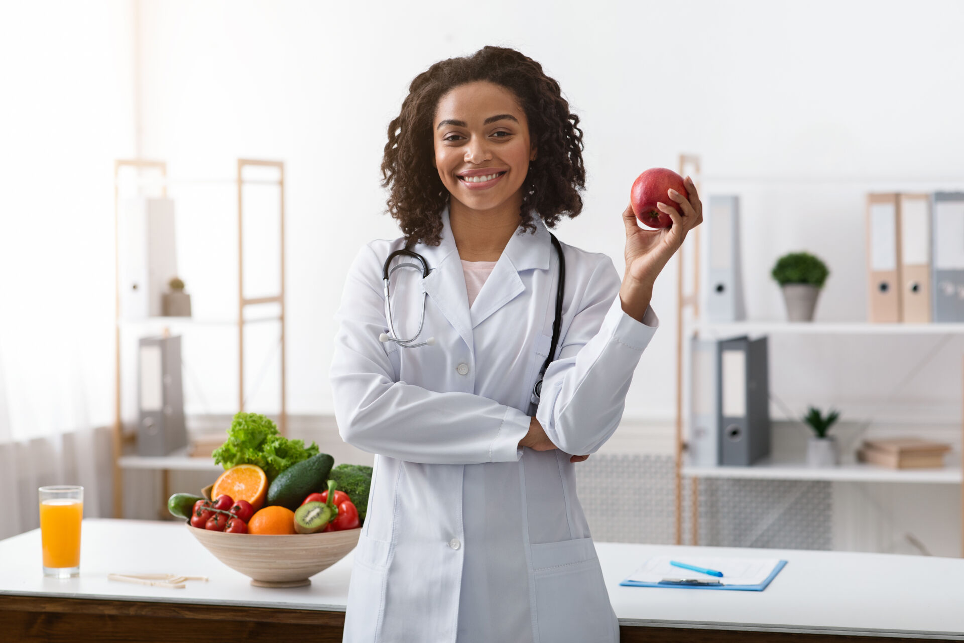 Pretty black lady dietologist holding apple in her hand Insurance for Dietitians
