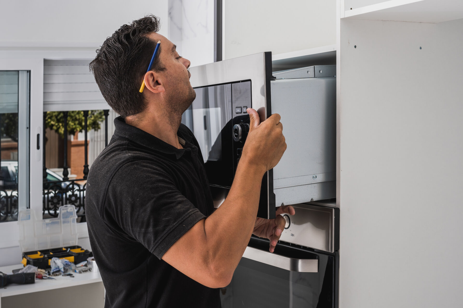 Man placing a microwave inside the hole of a new kitchen cabinet Installation