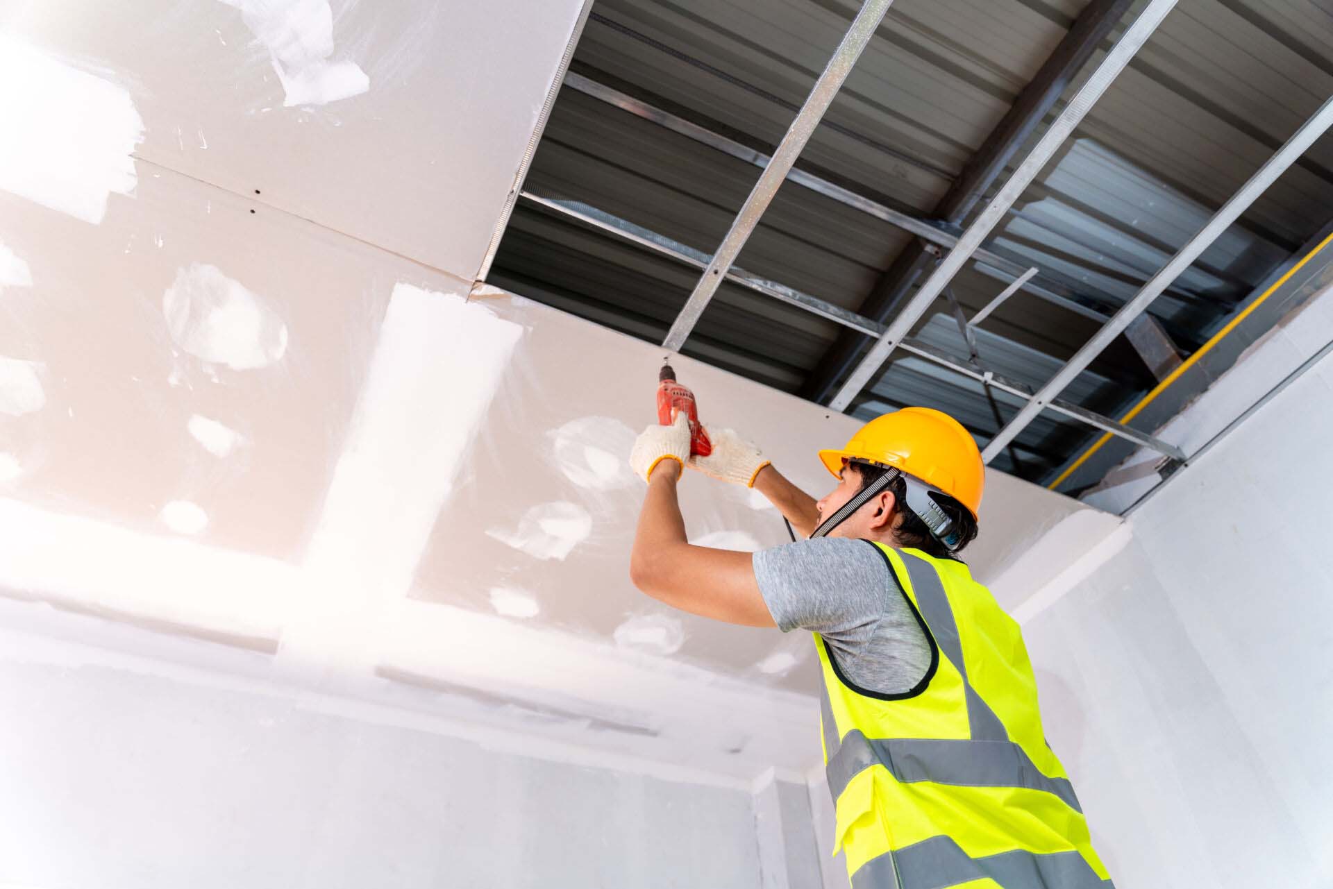 Construction workers using an electric drill are install the ceiling house at construction site, Ceiling installation ideas Insurance for Ceiling and Wall Installation Contractors