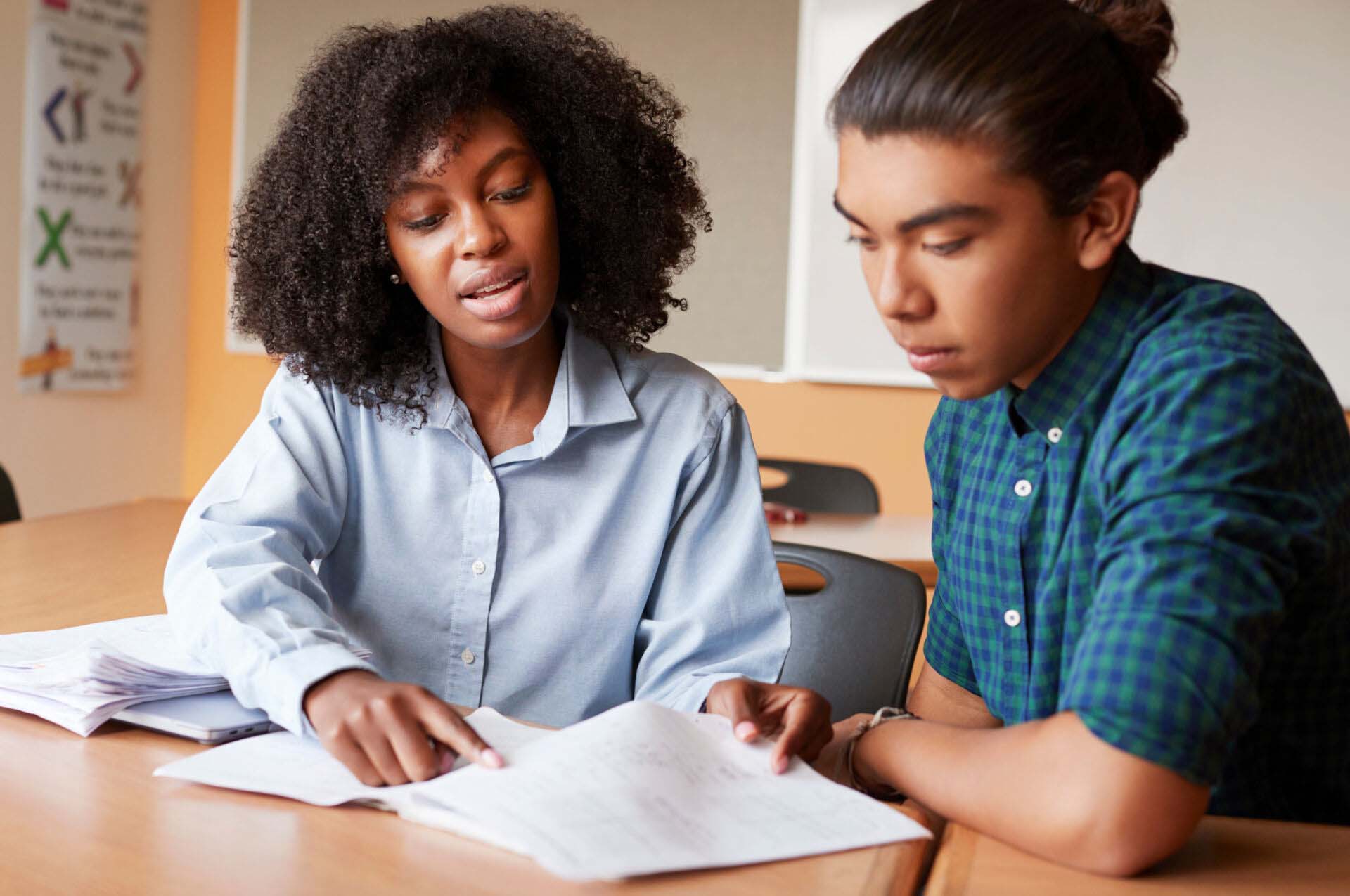 High School Tutor Giving Male Student One To One Tuition At Desk Insurance for Tutors