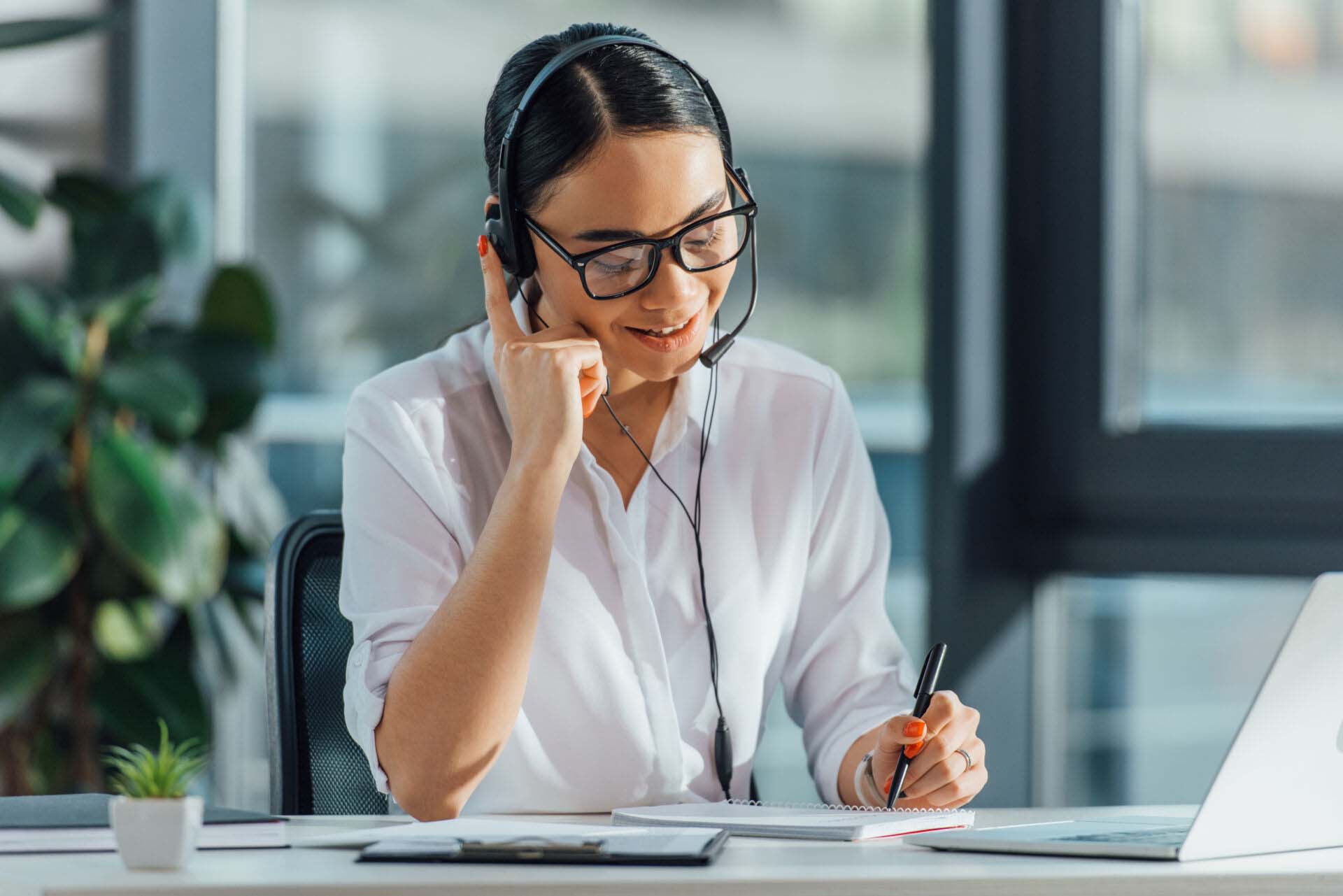 smiling asian translator working online with headset and laptop Insurance for Translators