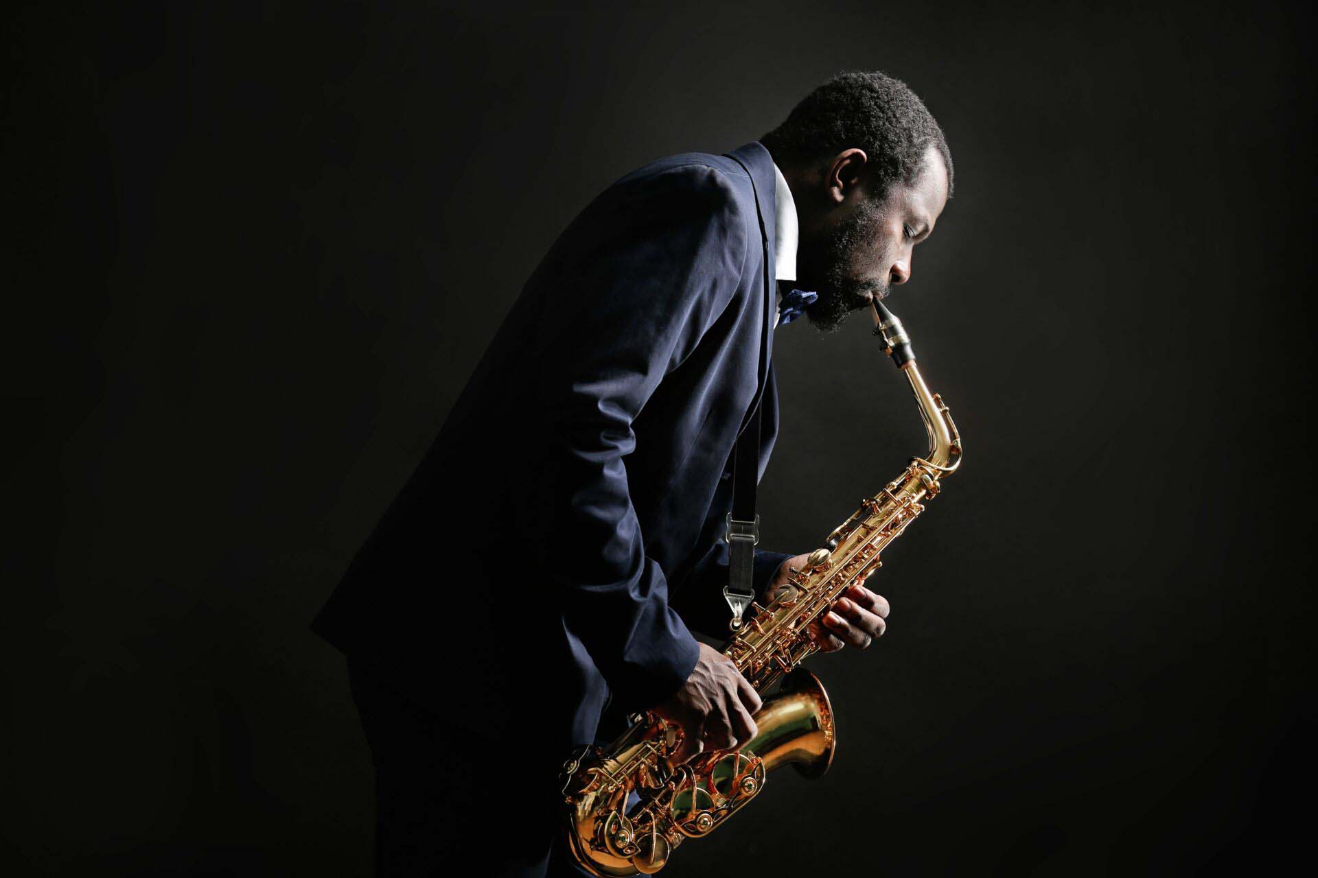 African American jazz musician playing the saxophone on grey bac Insurance for Musicians